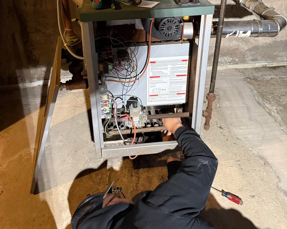 Brock's service tech laying on the ground repairing a furnace