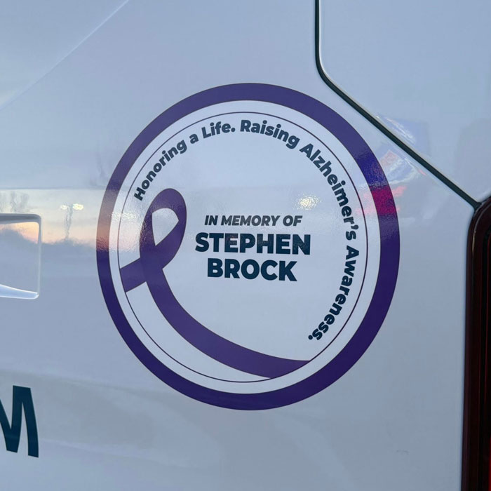 Round sticker with a purple ribbon that says Honoring a Life. Raising Alzheimer's Awareness. In Memory of Stephen Brock.