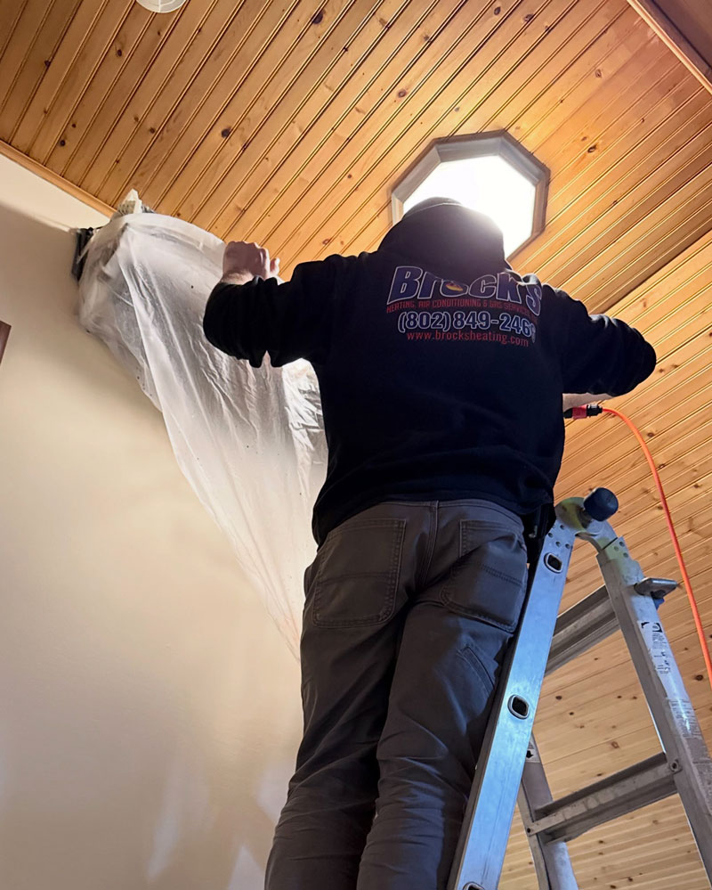 Technician covering a heat pump with a bag prior to cleaning