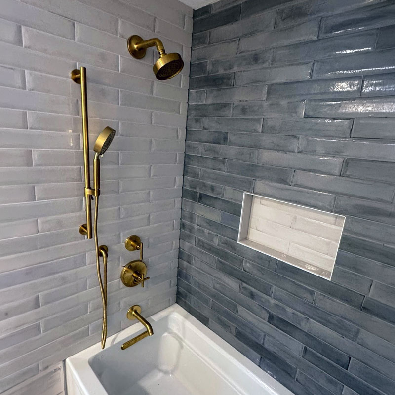 Newly installed shower hardware in a blue and white tile tub